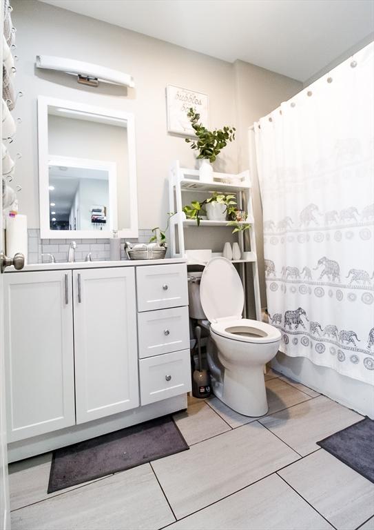 full bathroom featuring vanity, shower / bath combination with curtain, and toilet