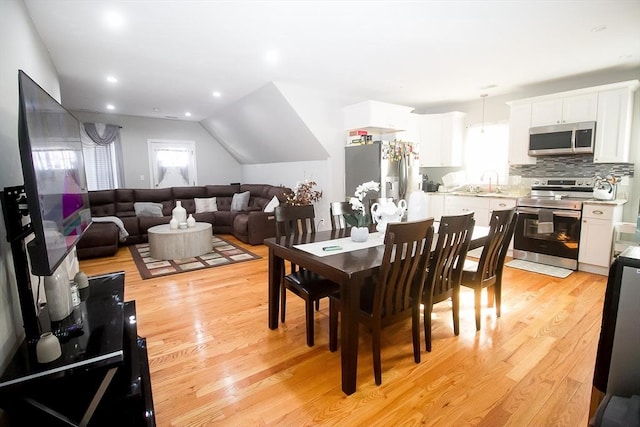 dining room with lofted ceiling, sink, and light hardwood / wood-style floors