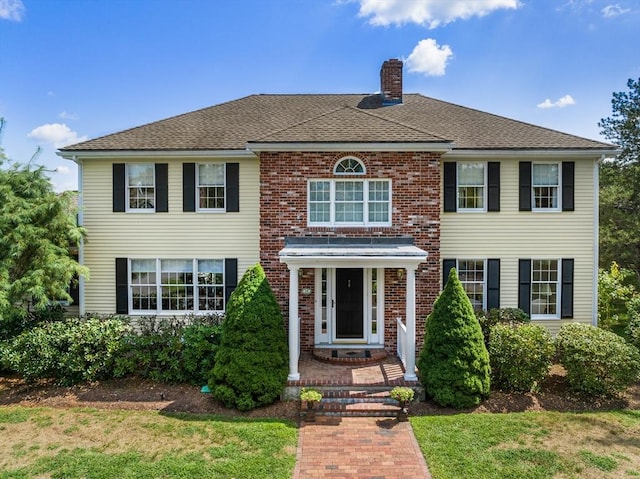 14 Frost Ln, Sudbury, MA 01776 - view of front facade with a chimney, brick siding, a front lawn, and a shingled roof