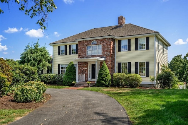 14 Frost Ln, Sudbury, MA 01776 - georgian-style home with a chimney, a front lawn, driveway, and brick siding