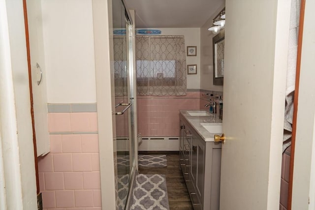 full bath featuring a wainscoted wall, wood finished floors, vanity, tile walls, and a stall shower