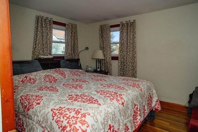 bedroom with multiple windows, wood finished floors, and baseboards