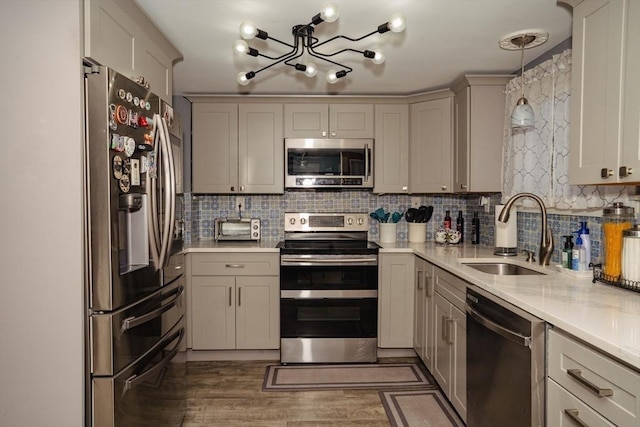 kitchen with light wood-style flooring, a sink, light countertops, appliances with stainless steel finishes, and backsplash