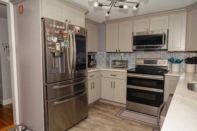 kitchen with appliances with stainless steel finishes, light countertops, light wood-style floors, and decorative backsplash