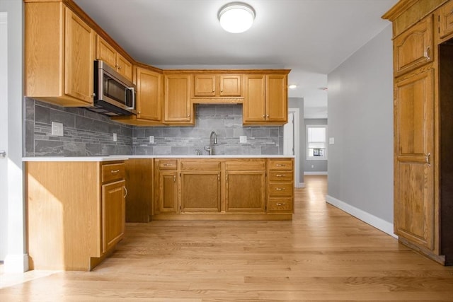 kitchen featuring sink, light hardwood / wood-style floors, and tasteful backsplash