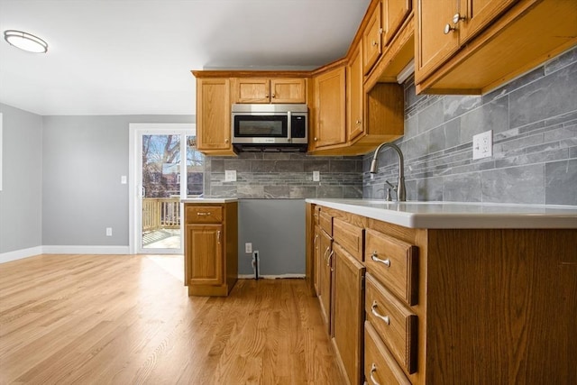 kitchen with sink, tasteful backsplash, and light hardwood / wood-style flooring