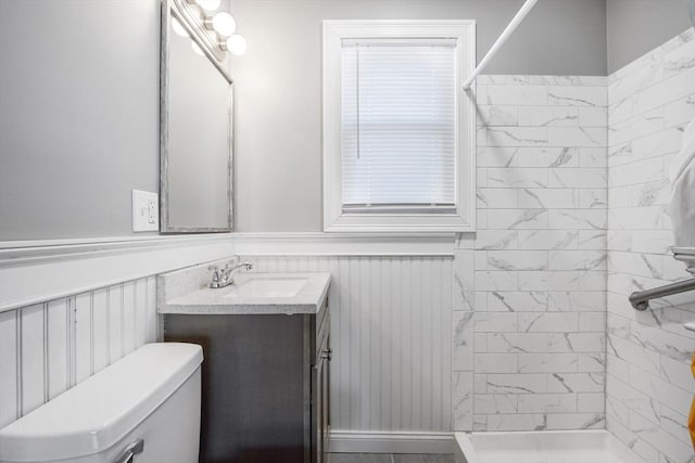 bathroom featuring toilet, vanity, and tiled shower