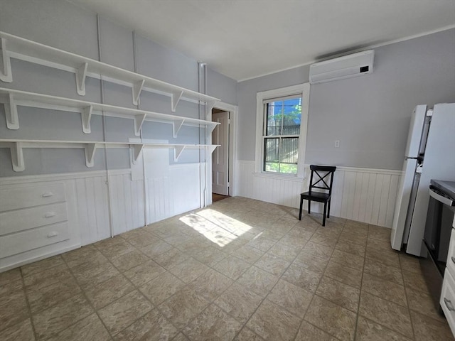 interior space featuring a wall unit AC, a wainscoted wall, and stone finish floors