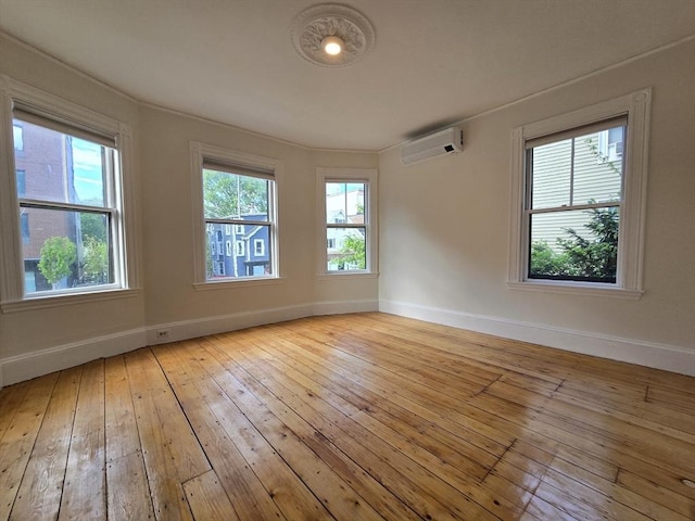 unfurnished room featuring an AC wall unit, hardwood / wood-style flooring, and baseboards