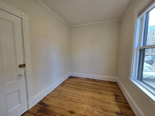 unfurnished room with wood-type flooring, crown molding, and baseboards