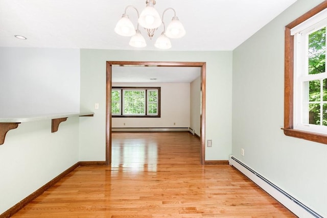 27 Woodland St, Natick, MA 01760 - empty room featuring a baseboard heating unit, a chandelier, light wood-style flooring, and healthy amount of natural light