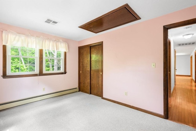 27 Woodland St, Natick, MA 01760 - empty room featuring a baseboard heating unit, baseboards, light colored carpet, and attic access