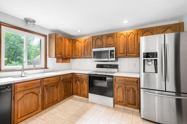 27 Woodland St, Natick, MA 01760 - kitchen featuring stainless steel appliances, a sink, brown cabinetry, light tile patterned floors, and light countertops