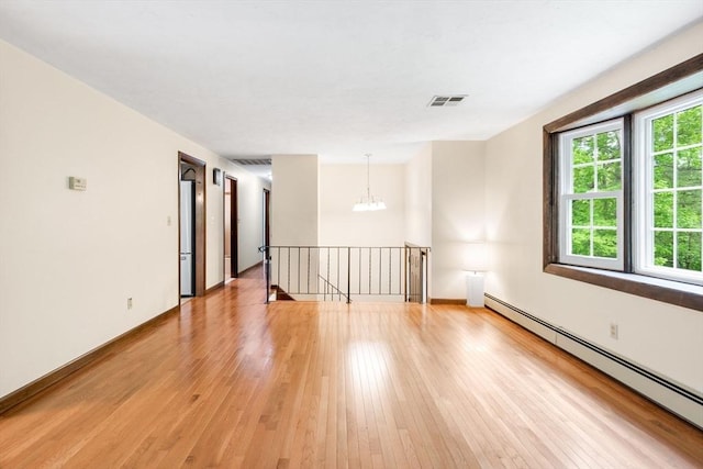 27 Woodland St, Natick, MA 01760 - unfurnished room with a baseboard heating unit, light wood finished floors, and a chandelier