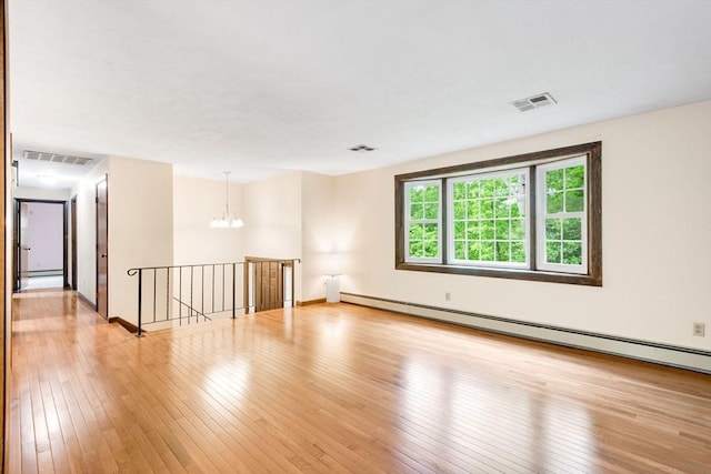 27 Woodland St, Natick, MA 01760 - empty room featuring a chandelier, a baseboard radiator, light wood-style floors, and baseboards