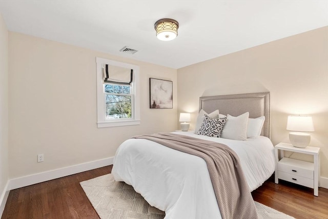 bedroom with visible vents, wood finished floors, and baseboards