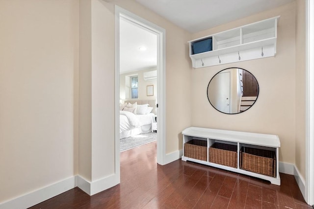 corridor featuring a wall unit AC, wood finished floors, and baseboards