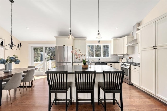 kitchen featuring dark wood finished floors, appliances with stainless steel finishes, a kitchen bar, tasteful backsplash, and a center island