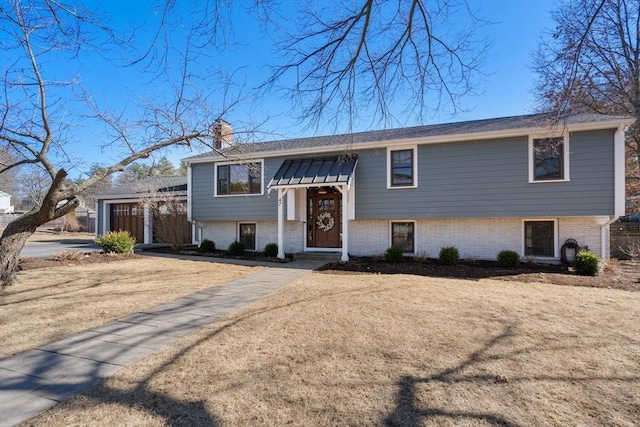 split foyer home featuring an attached garage, a chimney, and a front lawn