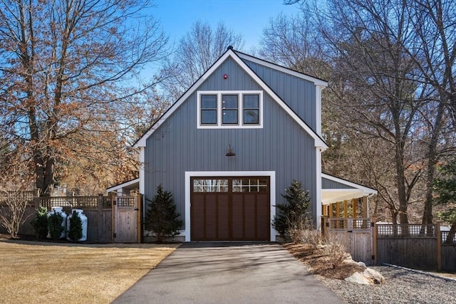 garage featuring driveway, fence, and a gate