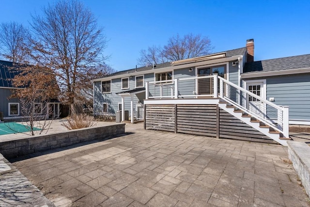 back of house featuring stairs, a patio, and a chimney