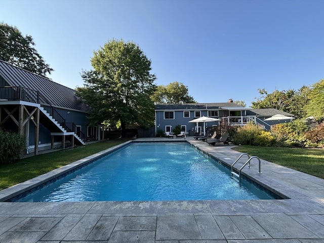 pool with stairway, a lawn, and a patio