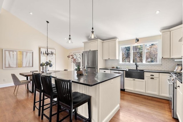 kitchen featuring a sink, dark countertops, wood finished floors, appliances with stainless steel finishes, and lofted ceiling