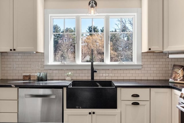 kitchen with a sink, decorative backsplash, dark countertops, and white cabinetry