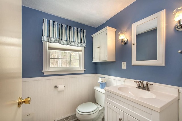 bathroom featuring visible vents, toilet, a textured ceiling, wainscoting, and vanity