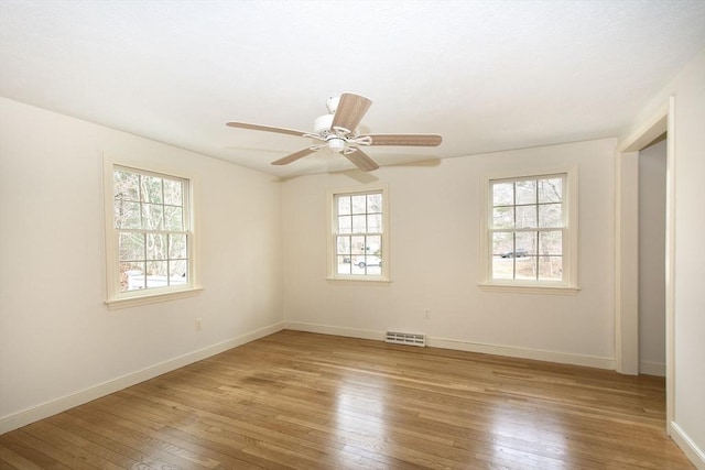 empty room featuring light wood-style flooring, baseboards, visible vents, and ceiling fan