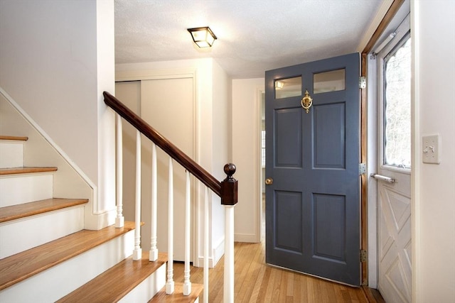 entrance foyer featuring a healthy amount of sunlight, wood finished floors, and stairs