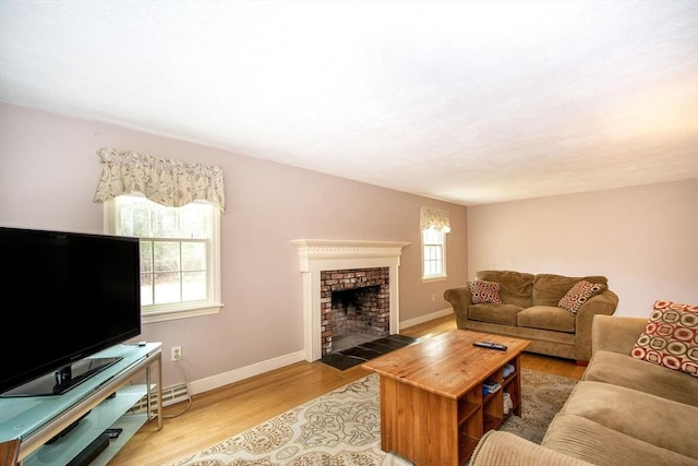 living area featuring baseboards, a brick fireplace, and light wood-style flooring