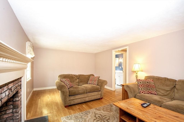 living room featuring baseboards, a fireplace, and light wood finished floors