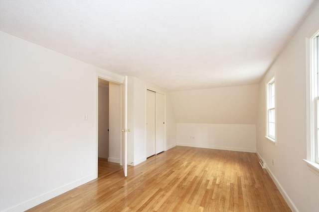 empty room with baseboards, lofted ceiling, and light wood-style flooring