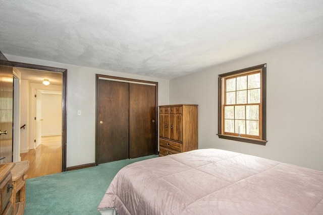 bedroom with baseboards, carpet, a closet, and a textured ceiling