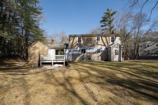 rear view of house with a yard, a wooden deck, and a chimney