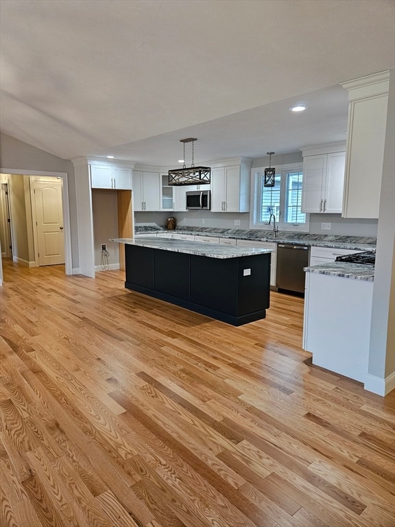 kitchen featuring pendant lighting, a center island, light hardwood / wood-style flooring, white cabinetry, and stainless steel appliances