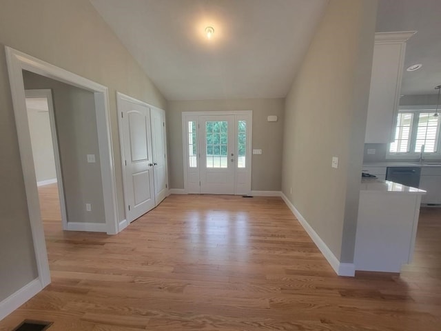 entryway with sink, light hardwood / wood-style floors, and lofted ceiling