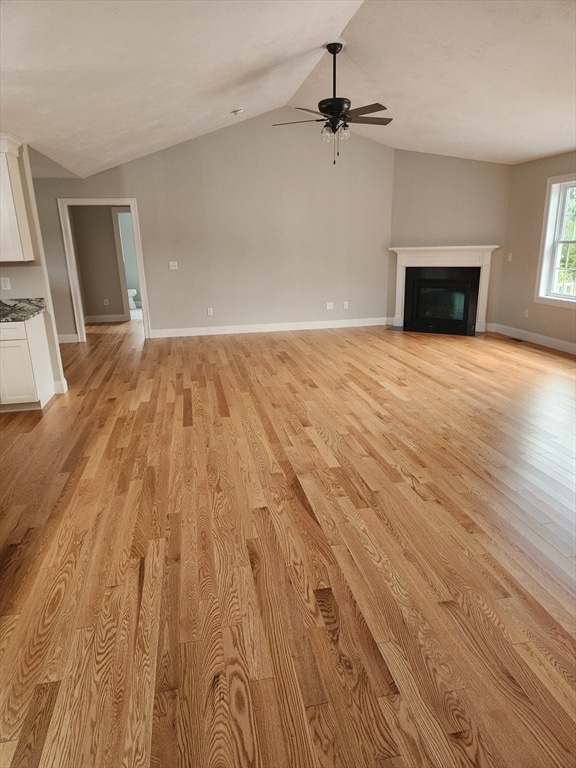 unfurnished living room with ceiling fan, light hardwood / wood-style floors, and vaulted ceiling