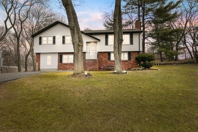 view of front facade with driveway, a chimney, a front lawn, and brick siding