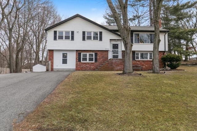 split foyer home featuring driveway, a front yard, and brick siding