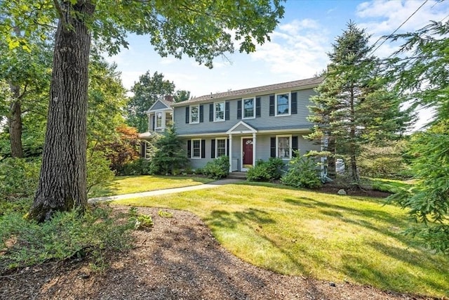 colonial home with a chimney and a front yard