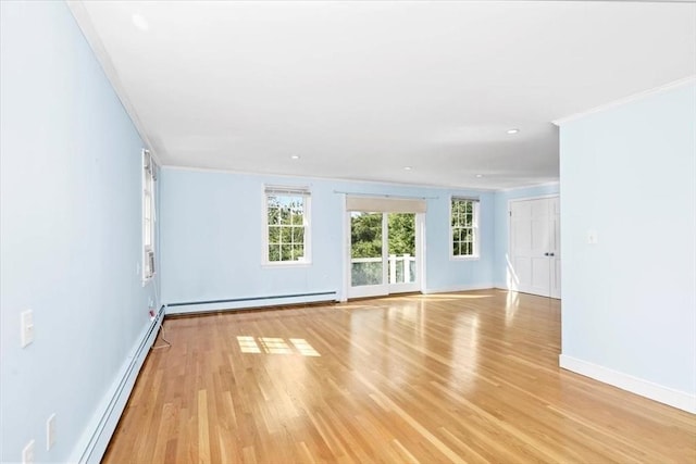 spare room with ornamental molding, light wood-type flooring, and baseboard heating