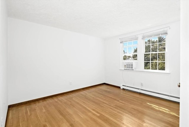 empty room with light hardwood / wood-style floors, a textured ceiling, and a baseboard heating unit