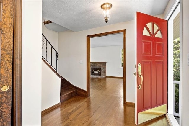 foyer featuring plenty of natural light, a textured ceiling, wood finished floors, and stairs