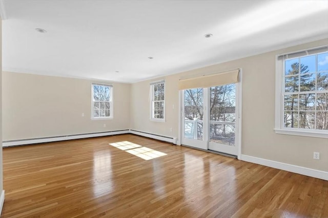 spare room featuring a baseboard radiator, wood finished floors, and baseboards