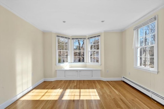 unfurnished room with baseboards, crown molding, baseboard heating, and light wood-style floors