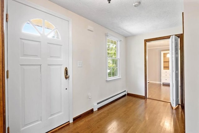 entrance foyer with a baseboard radiator, wood-type flooring, and a textured ceiling