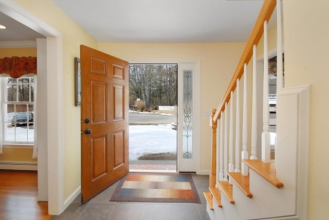 foyer entrance with a baseboard radiator, plenty of natural light, baseboards, and stairs