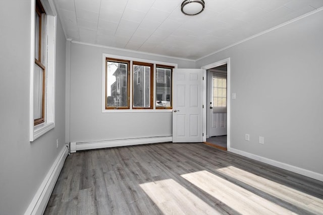 unfurnished room with ornamental molding, a baseboard heating unit, and light hardwood / wood-style floors